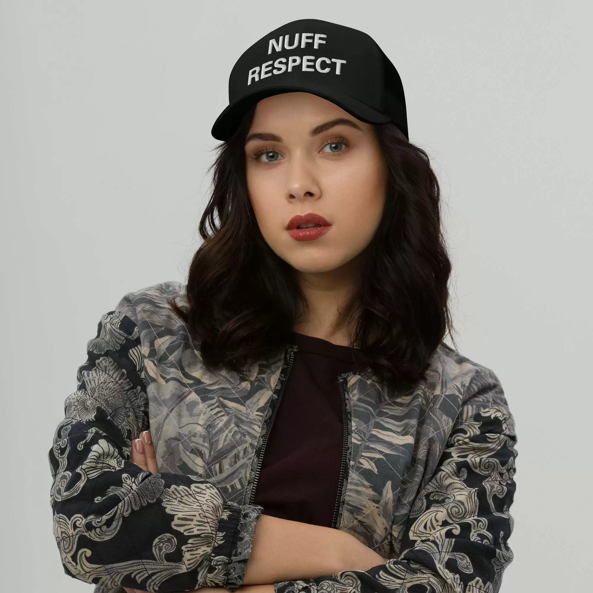Nuff Respect Jamaican Trucker Cap female view. Original embroidered Patois phrase on black trucker hat with mesh back and curved visor.