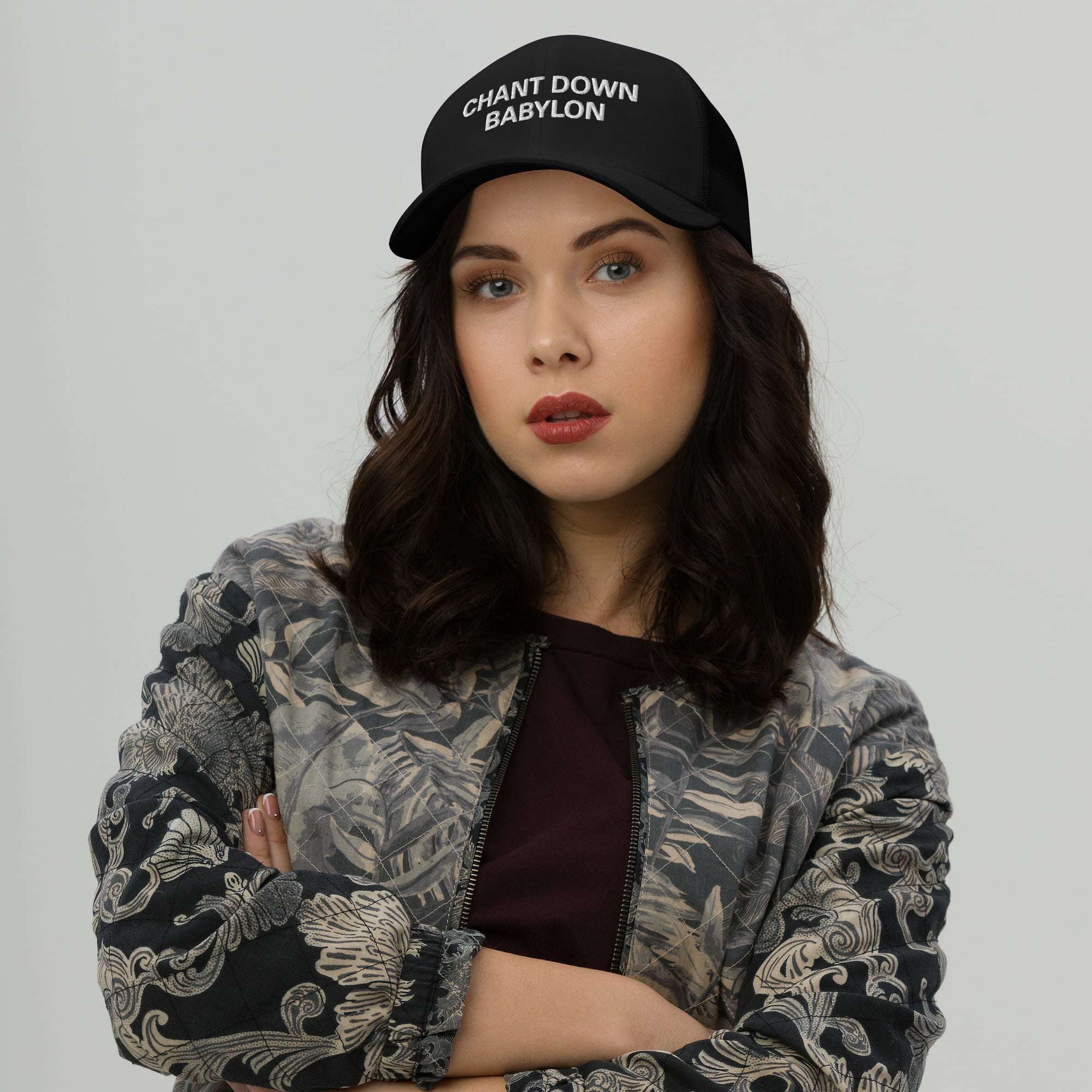 Rastafari hat front female model view with Chant Down Babylon embroidered across the front. Trucker style hat in black, great for vacation or Reggae Festival.
